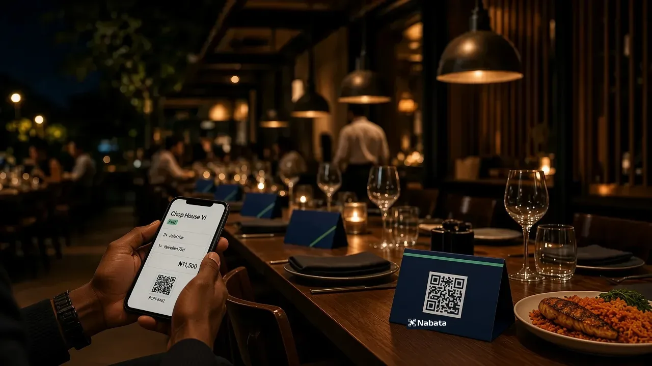 Navy Nabata QR tents on a Lagos restaurant table as a guest settles on their phone.